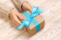 Woman`s hands give wrapped valentine holiday handmade present in craft paper with blue ribbon. Present box, decoration of gift on Royalty Free Stock Photo