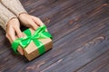 Woman`s hands give wrapped valentine holiday handmade present in craft paper with green ribbon. Present box, decoration of gift o Royalty Free Stock Photo