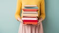 Woman's Hands Grasping Stack of Books Against Light Solid Background. Generative ai