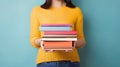 Woman's Hands Grasping Stack of Books Against Light Solid Background. Generative ai