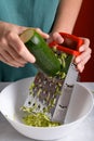 woman& x27;s hands grating green zucchini with a stainless steel hand grater, close up, food lifestyle Royalty Free Stock Photo