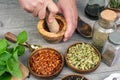 Woman`s hands grind red pepper in a wooden mortar. Kitchen gray table with various spices