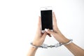 Woman`s hands in handcuffs holding smartphone on white background, virtual reality concept, social media addiction,