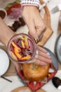 A woman`s hands hold a glass of mulled wine with cinnamon, sliced fruit on the background of a set table. Royalty Free Stock Photo