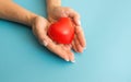 woman's hands hold a heart, blue background. a woman gives her love, an orphanage concept, a gift to mom for a holid