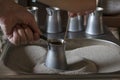 Woman`s hands hold metal turk while  preparing traditional turkish coffee in hot sand. Royalty Free Stock Photo