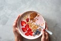 The girl`s hands hold a plate of yoghurt, granola and berries on a gray concrete background. Top view Royalty Free Stock Photo