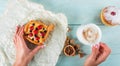 Woman`s hands hold a sweet pastrie with berries and coffee cup. Flat lay, top view