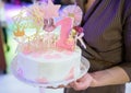 Woman`s hands hold White birthday cream cake with pink candles as decorations. Celebration, festive background, birthday party Royalty Free Stock Photo