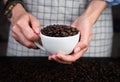 Woman`s hands hold a white cup with fresh fragrant coffee beans. Natural coffee. Close-up. Selective focus