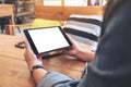 Woman`s hands holding black tablet pc with blank screen horizontally on wooden table in cafe Royalty Free Stock Photo