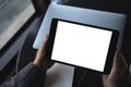 Woman`s hands holding black tablet pc with blank white desktop screen with laptop on table in cafe Royalty Free Stock Photo