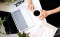 Woman`s hands holding cup of coffee in cozy office with laptop and green plants Royalty Free Stock Photo