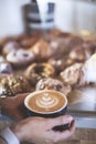 Woman`s hands holding a cup of signature coffee prepared by a barista next to a counter full of croissants. Restaurant. Quiet Royalty Free Stock Photo