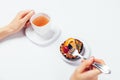 Woman's hands holding cup tea and fork to eat fruit dessert Royalty Free Stock Photo