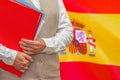 Woman`s hands holding documents against Spain flag background. Education abroad