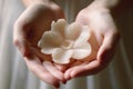 Woman\'s hands holding a flower-shaped wax shaving product, highlighting the connection between femininity,