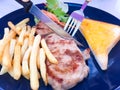 The woman`s hands are holding a fork and knife to cut the steak.  This is Grilled Pork chop Steak with gravy sauce, there are Royalty Free Stock Photo