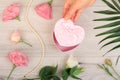 Woman`s hands holding a gift box on gray wooden background with beautiful flowers and green leaves. Royalty Free Stock Photo