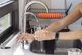 Woman& x27;s hands holding a glass that fills with water from the tap filter