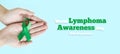 Woman& x27;s hands are holding green ribbon - symbolizing fight against disease. World lymphoma awareness day. September