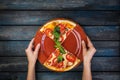 Woman`s hands holding a plate with two pieces of pizza margarita with tomato slices, olives and basil leaves. Top view Royalty Free Stock Photo