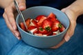 Woman`s hands holding smoothie or granola bowl topped with fresh strawberry. Healthy breakfast concept Royalty Free Stock Photo