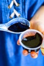 Woman`s Hands Holding Spoon with Black Chinese Herb Jelly Named Guiling Gao