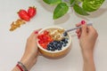 WomanÃÂ´s hands holding spoon and bowl of healthy homemade breakfast. Yogurt with strawberries, blueberries and nuts, Royalty Free Stock Photo