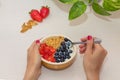 WomanÃÂ´s hands holding spoon and bowl of healthy homemade breakfast. Yogurt with strawberries, blueberries and nuts. Royalty Free Stock Photo