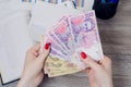 Woman`s hands holding Ukrainian money over desktop