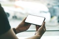 A woman`s hands holding and using black mobile phone with blank screen while sitting in the airport Royalty Free Stock Photo