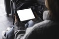 Woman`s hands holding and using black tablet pc with blank white desktop screen while sitting on the floor with baggages