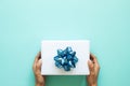 Woman`s hands holding white gift box with blue ribbon on pastel Royalty Free Stock Photo