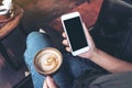 Woman`s hands holding white mobile phone with blank black desktop screen while drinking coffee in cafe Royalty Free Stock Photo