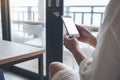 A woman`s hands holding white mobile phone with blank black desktop screen in loft cafe Royalty Free Stock Photo