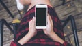 Woman`s hands holding white mobile phone with blank black screen on thigh with wooden floor background in vintage cafe Royalty Free Stock Photo