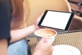 Mockup image of woman's hands holding tablet with blank screen while drinking coffee in modern cafe Royalty Free Stock Photo