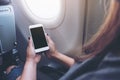 Woman`s hands holding a white smart phone with blank black desktop screen next to an airplane window Royalty Free Stock Photo