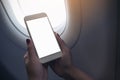 Woman`s hands holding a white smart phone with blank desktop screen next to an airplane Royalty Free Stock Photo