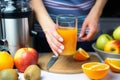 Woman`s hands holds glass with freshly squeezed multivitamin juice. Natural and healthy juices at home. Close-up. Selective focus