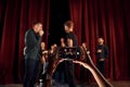 Woman`s hands holds phone and taking picture. Group of actors in dark colored clothes on rehearsal in the theater