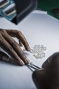 Woman`s hands inspecting rough diamonds with forceps.