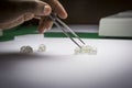 Woman`s hands inspecting rough diamonds with forceps. Royalty Free Stock Photo