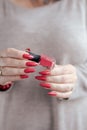 Woman`s hands and a bottle of red orange nail polish Royalty Free Stock Photo