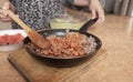 Woman`s hands mixing beans with ground beef in a black metal pan