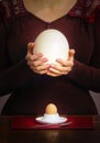 Woman`s hands with ostrich egg near a table with an eggcup and a Royalty Free Stock Photo