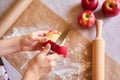 Woman`s hands peeling an apple. Baking ingredients placed on table, ready for cooking. Concept of food preparation, white table o Royalty Free Stock Photo