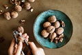 Woman`s hands peeling walnuts with a nutcracker on a table