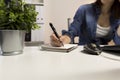 Woman`s hands with pen writing on notebook. Modern grey office d